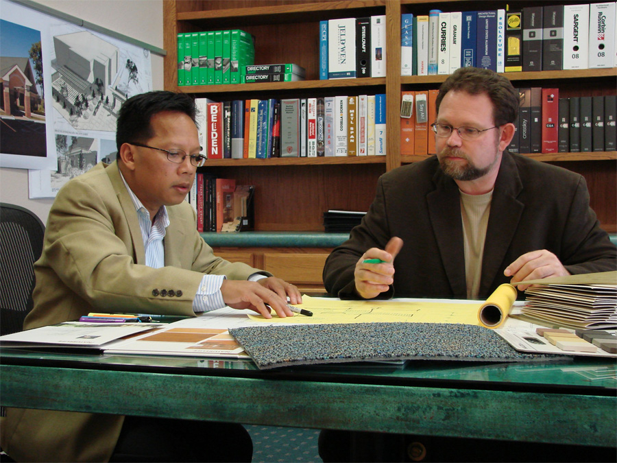 Dental Office Designers Jim and HanH at table going over plans. 