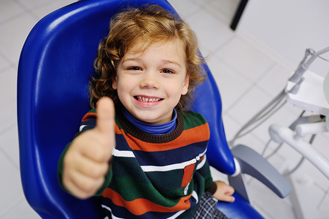 happy pediatric dental patient in office exam chair