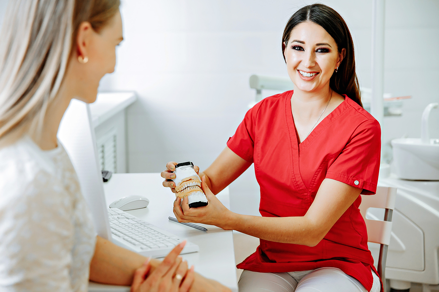 Smiling dentist talking to a patient in a modern dental office.