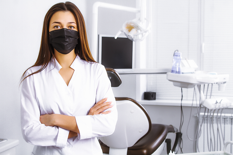 Dentist standing in a treatment room wearing a mask.